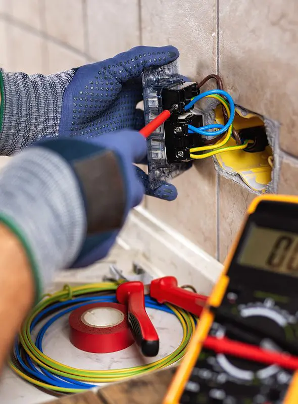 Electrician working on wall socket wiring.