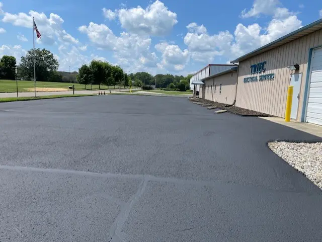 Freshly paved parking lot beside a building under a blue sky.